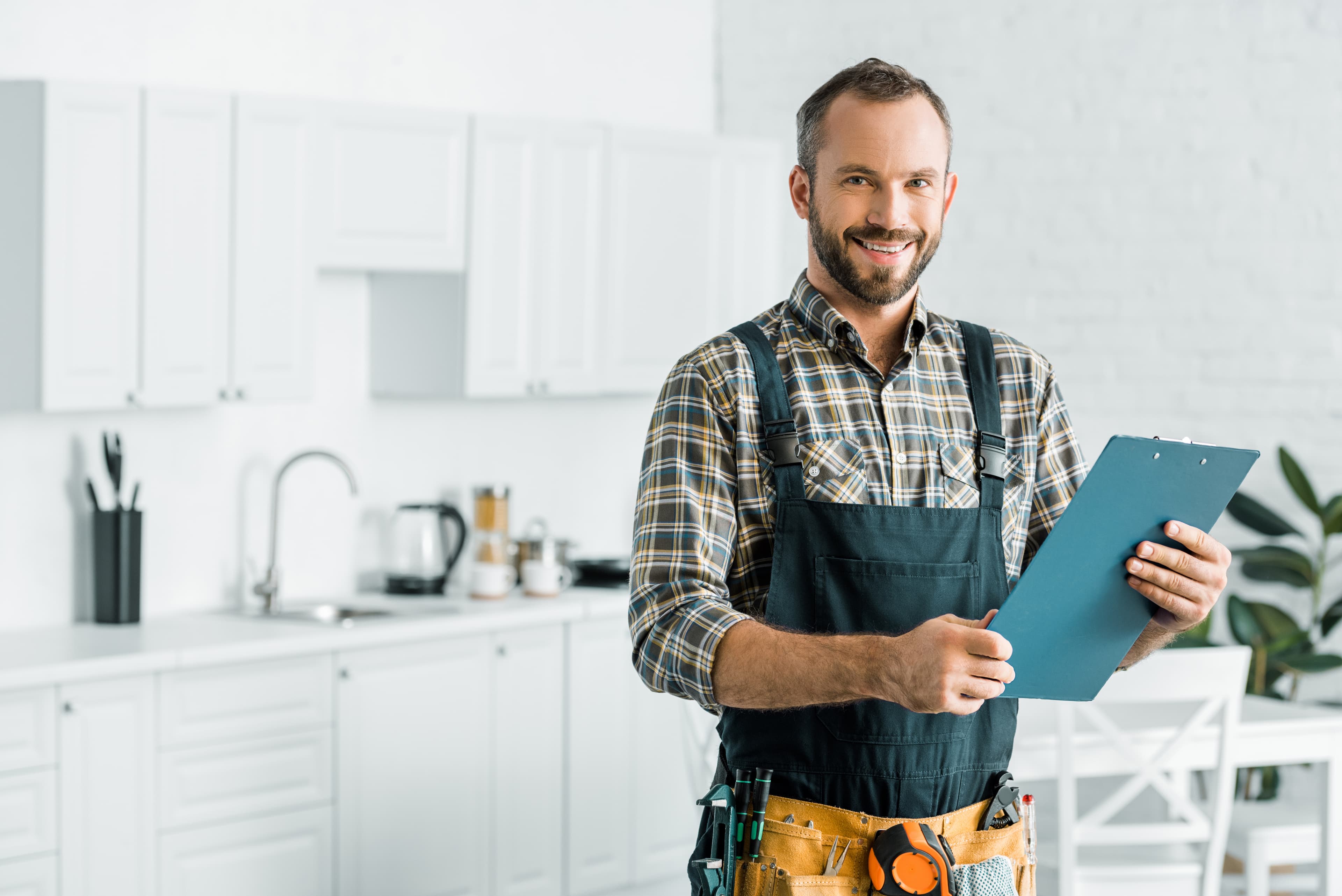 Professional plumber with clipboard in kitchen